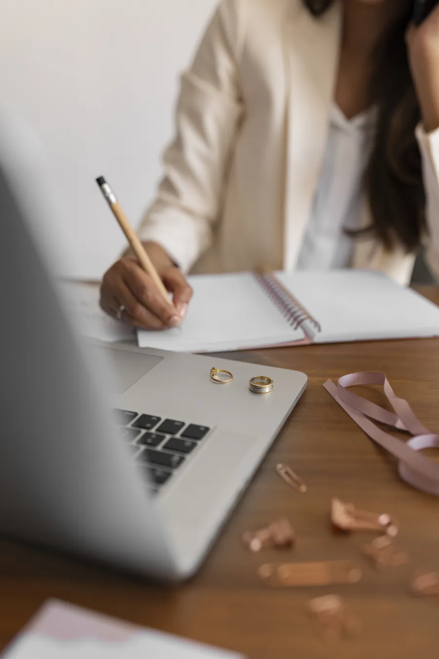 A person writing planning notes beside a laptop.