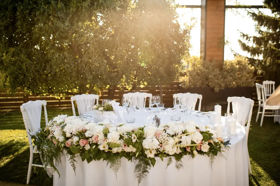 White wedding flowers along a table in warm evening light.